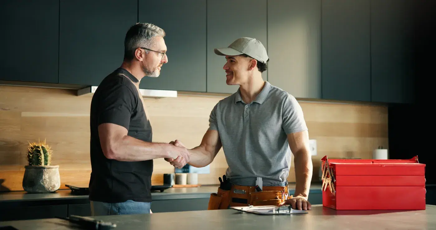 A Quotsey contractor shaking hands with a happy homeowner in their kitchen