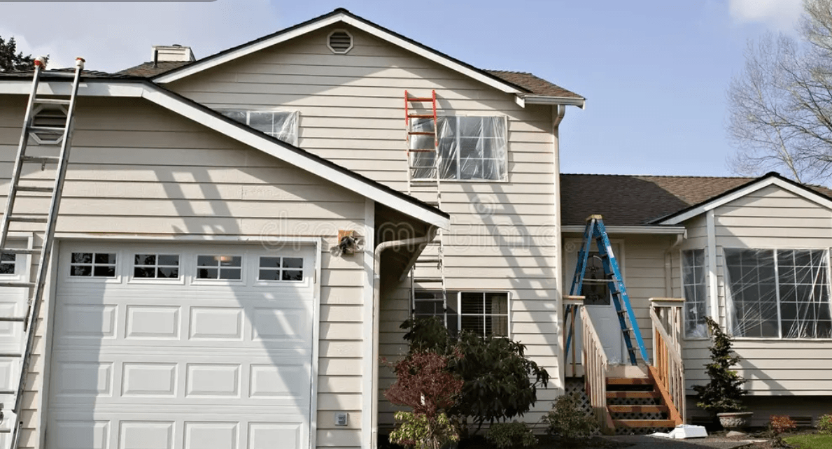 House exterior being prepped for painting with ladders and plastic sheeting
