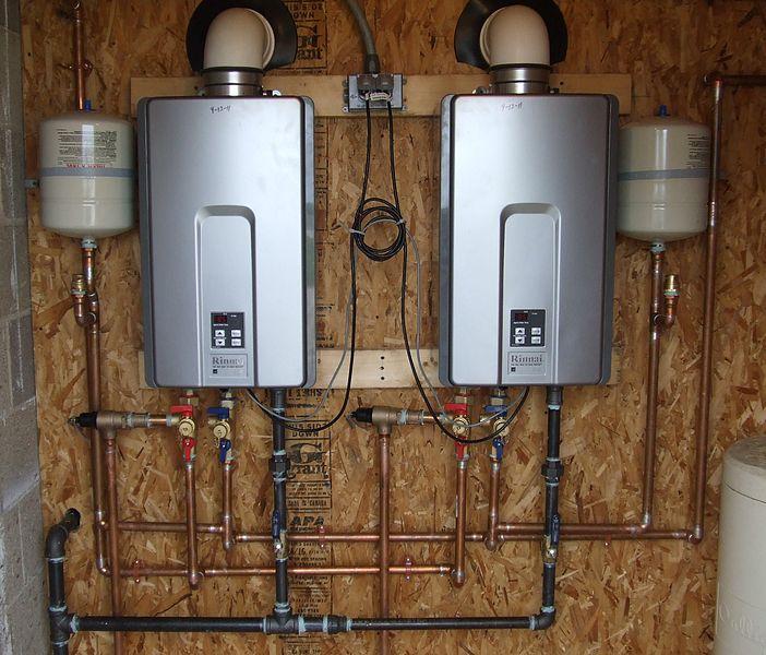 Two Rinnai tankless water heaters mounted on wall with copper plumbing