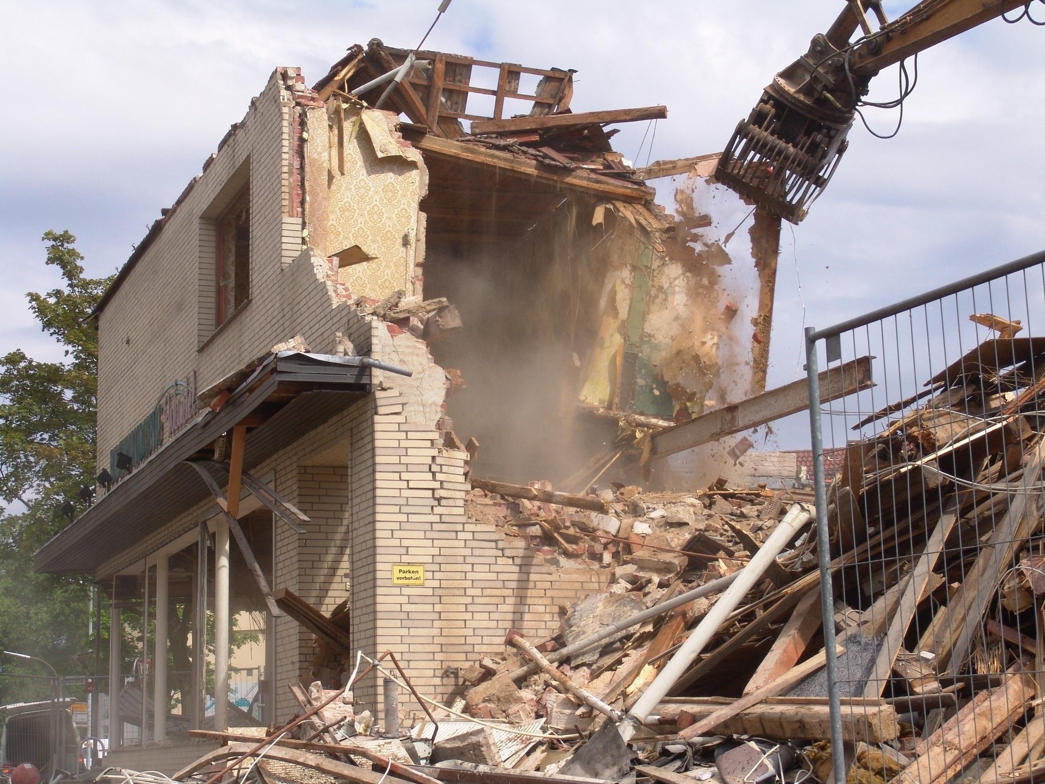 Building being demolished with excavator during major renovation